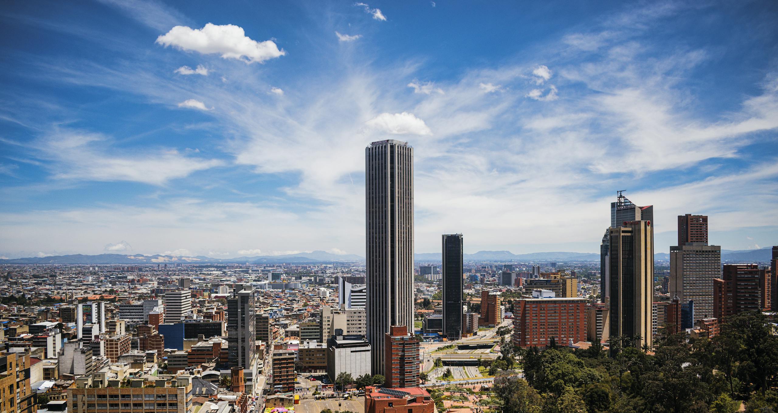 A breathtaking cityscape of Bogotá with the iconic Colpatria Tower under a vibrant blue sky.