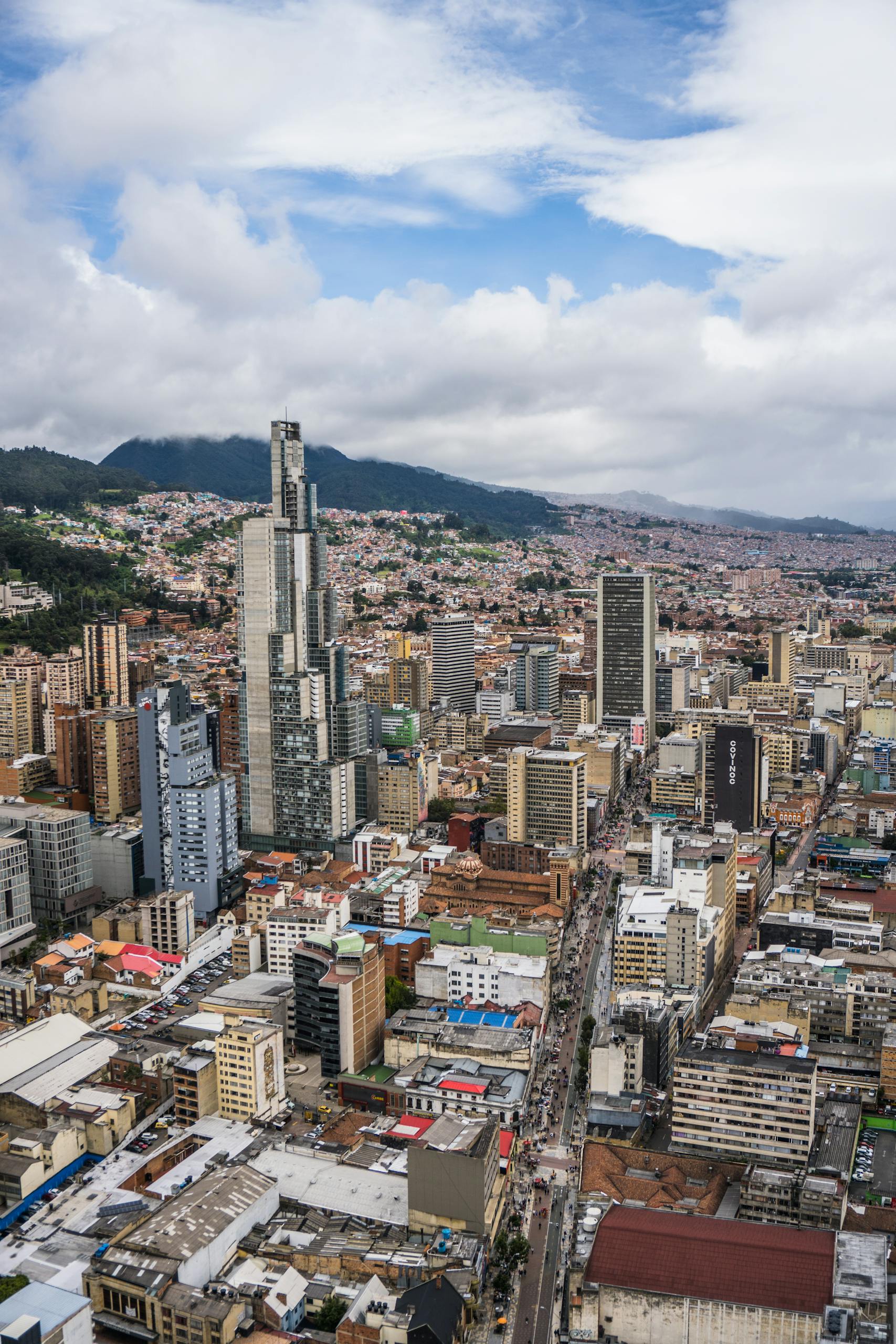 A bustling urban cityscape of Bogotá with iconic skyscrapers under a cloudy sky.