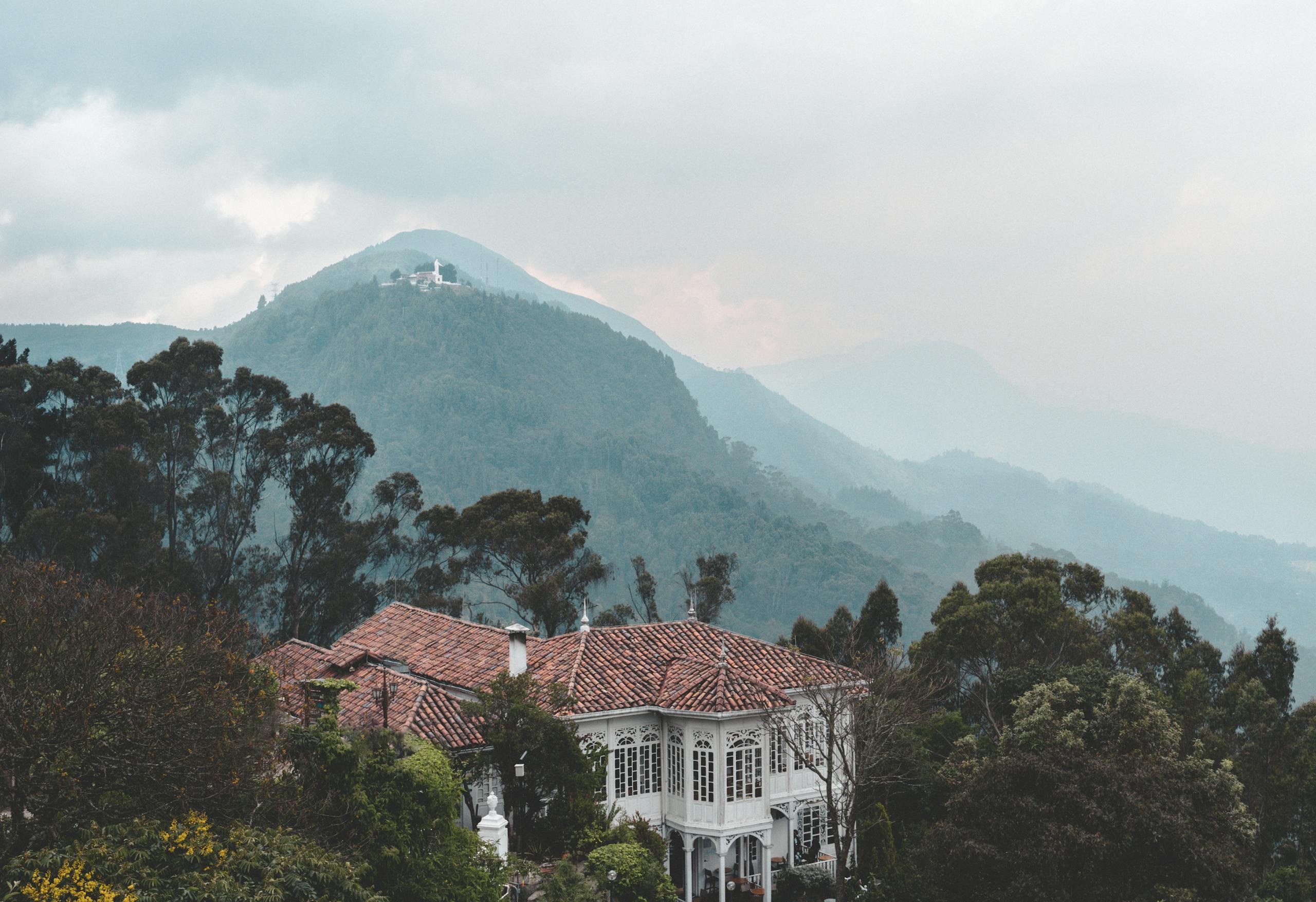 Charming Casa Santa Clara nestled in lush Colombian mountains with misty landscape.